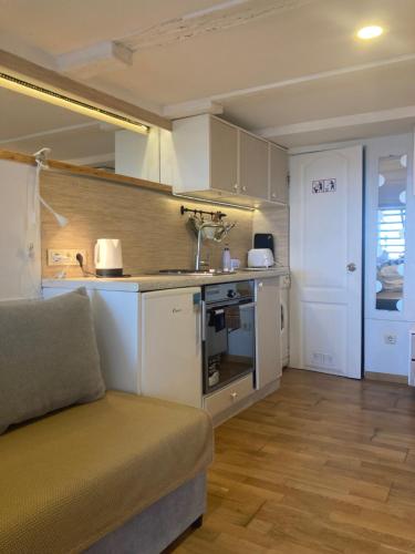 a kitchen with white cabinets and a couch in a room at Curonian Coast studio in Nida