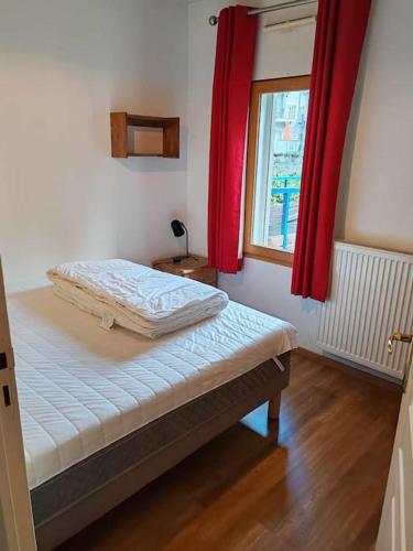 une chambre avec un lit avec des rideaux rouges et une fenêtre dans l'établissement Appartement familial en résidence Saint Gervais les bains, à Saint-Gervais-les-Bains