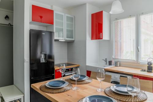 - une cuisine avec 2 tables et des verres à vin dans l'établissement Appartement F3 55m2 à 5' de Paris, à Ivry-sur-Seine