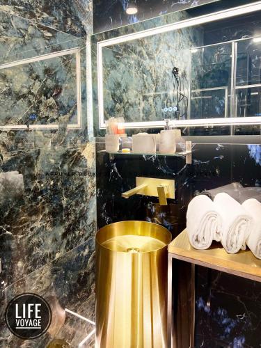 a bathroom with a gold sink and a pile of towels at LiFE VOYAGE RESIDENCE & SPA - Strasbourg's City Center Luxury Experience in Strasbourg
