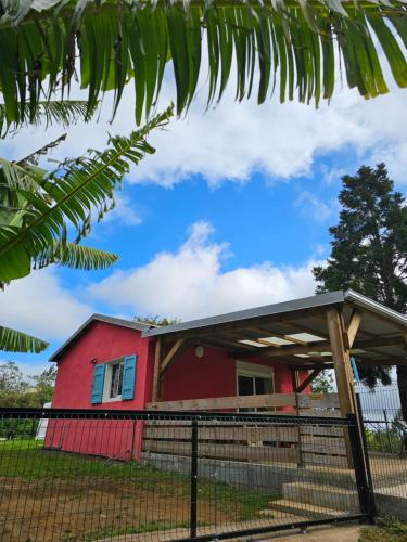 a red house with a fence in front of it at Au coeur des plantations in La Possession
