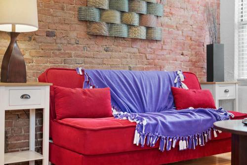 a red couch with purple and red pillows next to a brick wall at Panoramic Views on Your Front Porch in Pittsburgh