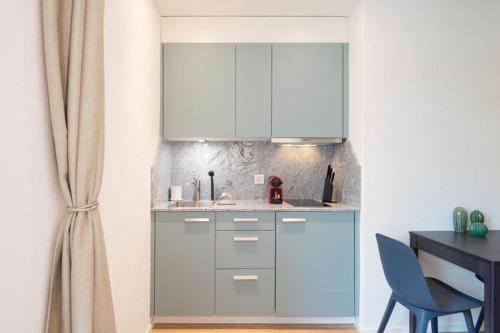 a kitchen with white cabinets and a table at HITrental Riesbach Apartments in Zürich