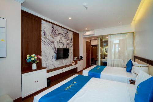 une chambre d'hôtel avec deux lits et une télévision dans l'établissement CORDELIA HA LONG Hotel, à Hạ Long