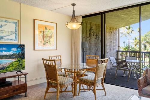 a dining room with a table and chairs and a balcony at Maui Sunset B211 in Kihei