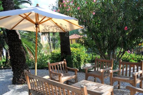 two wooden benches with a table and an umbrella at Hotel Villa Adriana in Monterosso al Mare