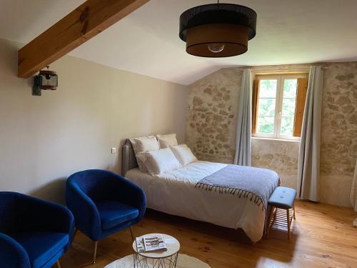 a bedroom with a bed and two blue chairs at La Grange de garac in Saint-Christaud