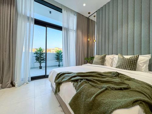 a bedroom with a large bed and a large window at Bright New Studio with Pool & Gym Access, 5 min from Gardens Metro in Dubai