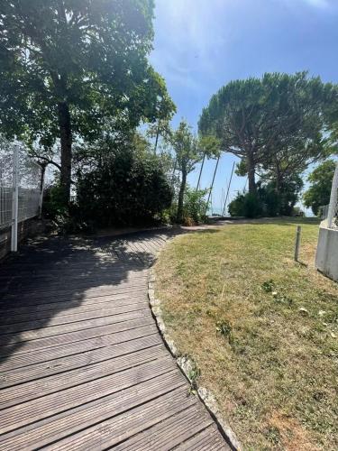 une passerelle en bois menant à un parc arboré dans l'établissement Maison bord de mer, à Saint-Georges-de-Didonne