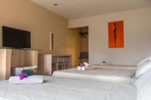 a hotel room with two beds and a flat screen tv at Pousada New Paradise in Búzios