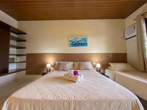 a bedroom with a large white bed with two pillows at Pousada New Paradise in Búzios