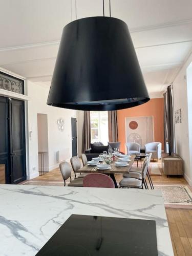 un salon avec une table à manger et un grand éclairage noir dans l'établissement Au cœur de Bourges, à Bourges