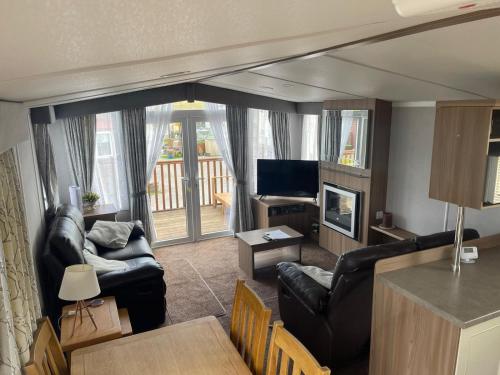 a living room with black leather furniture and a television at Lake District Stunning Lodge in Plumbland