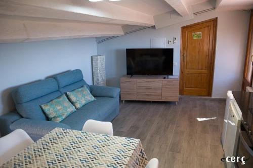 a living room with a blue couch and a flat screen tv at Casa Garí in Horta de San Joan