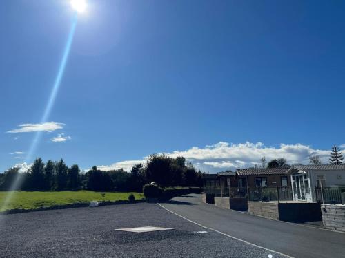 a road with a house and the sun in the sky at Lake District Stunning Lodge in Plumbland