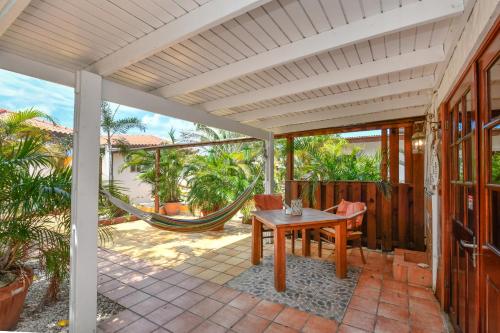 a porch with a hammock and a table and chairs at Brisas Studio Apartments in Palm-Eagle Beach