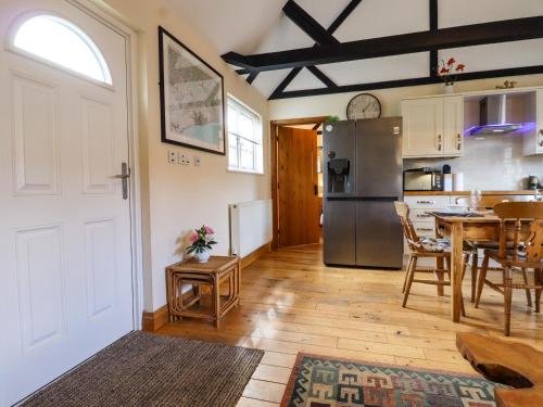 a kitchen and dining room with a table and a refrigerator at White Hart Stables in Battle