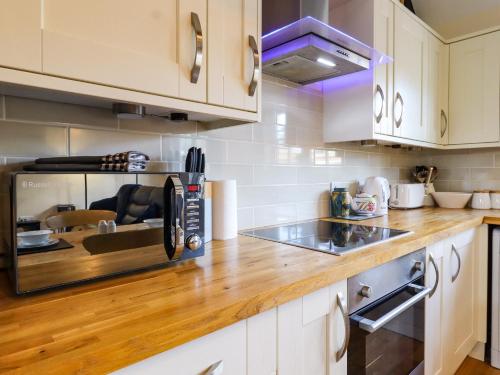 a kitchen with a microwave and a wooden counter top at White Hart Stables in Battle