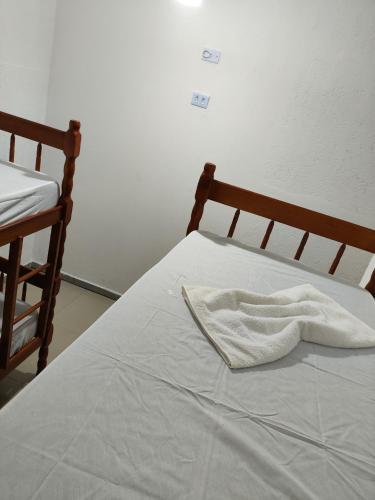 a bed with a white blanket on it at Olegário Bueno 230 in Hortolândia