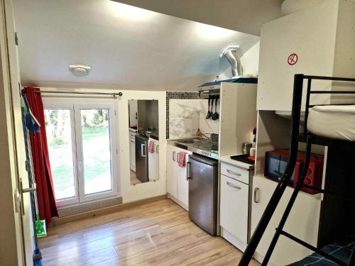 a small kitchen with white cabinets and a window at 10 - Joli studio avec deux lits, un lit double et un lit simple, logement tout équipé pour 1, 2 ou 3 personnes maximum, vue sur parc arboré, parking privatif gratuit, grand fourgon possible, tout le linge de maison est fourni in Razac-sur-lʼIsle