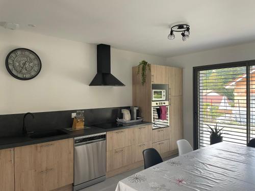 une cuisine avec des placards en bois, une table et une horloge dans l'établissement Maison à la campagne en chanvre, à La Chevillotte