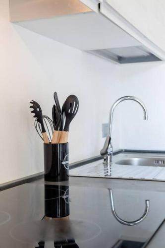 a container of kitchen utensils on a counter next to a sink at [Gardaland_Luxury_Apartment] Pool & Free Parking in Ronchi