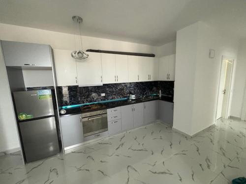 una cucina con mobili bianchi e un frigorifero di Armonia a Durrës