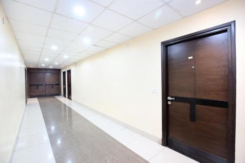 an empty corridor with a wooden door in a building at Hotel O Emblem in Ludhiana