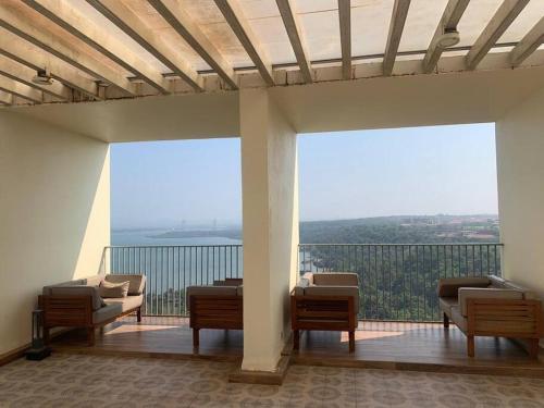 a balcony with chairs and a view of the water at Goodstay Sunlit Bliss Cozy2BHK with Luxe Touch704 in Dabolim