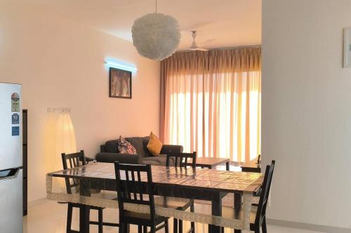 a dining table and chairs in a living room at Goodstay Sunlit Bliss Cozy2BHK with Luxe Touch704 in Dabolim