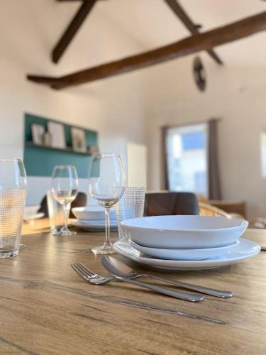 a wooden table with plates and wine glasses on it at Sous les toits de Bourges in Bourges