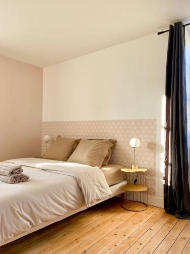 a white bedroom with a bed and a side table at Sous les toits de Bourges in Bourges