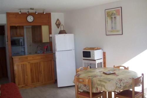 une cuisine avec une table et un réfrigérateur blanc dans l'établissement #AH3 The Snow White, à Huez