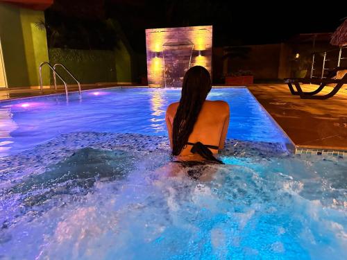 a woman sitting in a swimming pool at night at KETHALYA TAYRONA Hostal in El Zaino