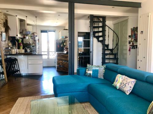 - un canapé bleu dans un salon avec une cuisine dans l'établissement Duplex atypique proche Montparnasse & parc expositions, à Paris