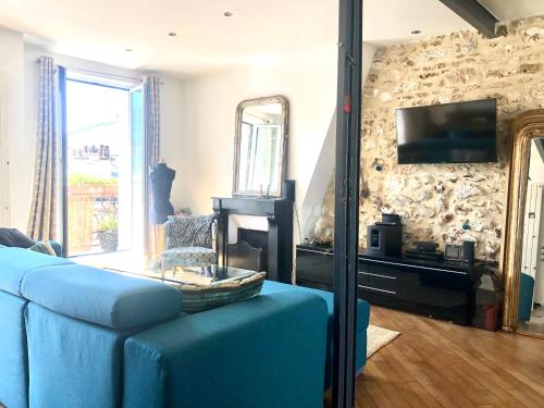 un salon avec un canapé bleu et une télévision dans l'établissement Duplex atypique proche Montparnasse & parc expositions, à Paris