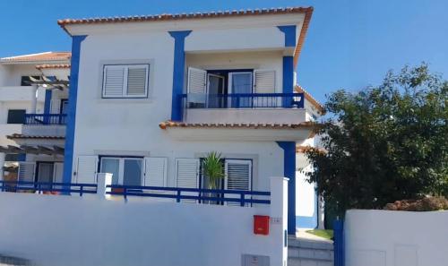 a white house with blue trim and a fence at Villa Alegria in Ericeira