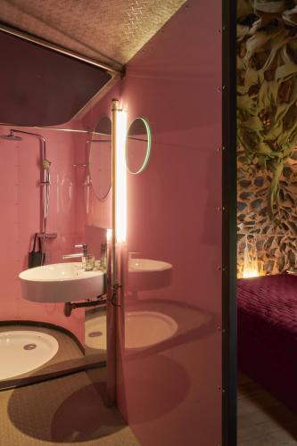 une salle de bain rose avec un lavabo et un miroir dans l'établissement La Colline du Colombier, à Iguerande