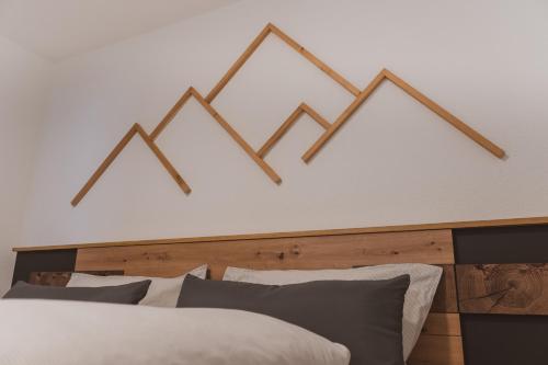 a bedroom with a white bed with a wooden headboard at Apart Zirmegg in Tobadill