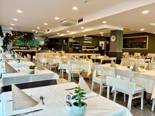 a restaurant with white tables and white chairs at Hotel Alfieri in Sirmione