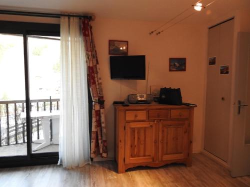 un salon avec une télévision et une fenêtre dans l'établissement studio aux pieds des cimes, à Enchastrayes