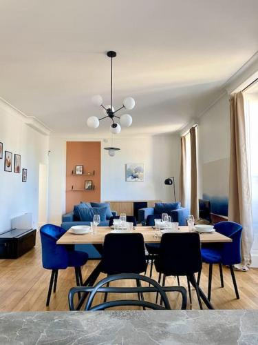 a dining room and living room with a table and blue chairs at Au pied de la Cathédrale de Bourges in Bourges