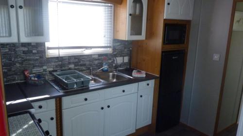 a kitchen with white cabinets and a sink and a window at L3 Millfields 4 Berth Luxury Caravan DG & GCH Family's Only And Lead Person Must Be Over 30 in Ingoldmells