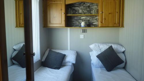 a corner of a room with two beds and cabinets at L3 Millfields 4 Berth Luxury Caravan DG & GCH Family's Only And Lead Person Must Be Over 30 in Ingoldmells