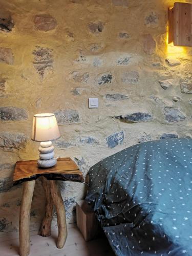 a lamp on a table next to a bed at Gîte de ferme équestre in Auzet