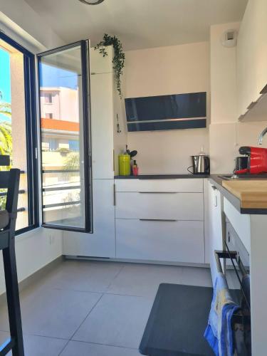 une cuisine avec des placards blancs et une grande fenêtre dans l'établissement PWS - Sunny modern flat near Juan Les Pins Pinede & beach - Terrace & AC!, à Antibes