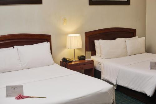 a hotel room with two beds and a lamp at El Dorado Classic Hotel in Iquitos