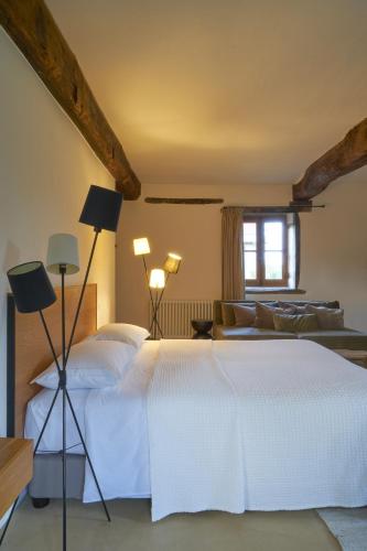une chambre avec un lit blanc et un canapé dans l'établissement La Colline du Colombier, à Iguerande