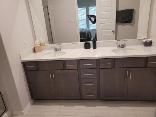 a bathroom with two sinks and a large mirror at Ts3 Houston in Missouri City