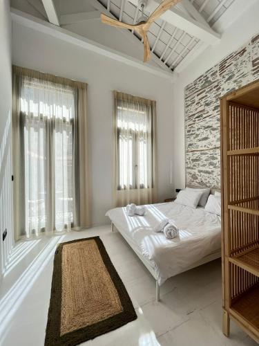 a white bedroom with a bed and a brick wall at The Bridge House Plomari in Plomari